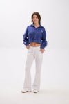 Woman wearing a blue tracksuit with a logo on a white background.