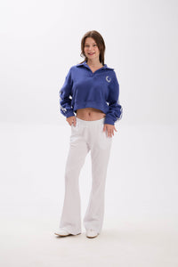 Woman wearing a blue tracksuit with a logo on a white background.