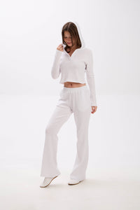 Woman wearing a white outfit on a white background.