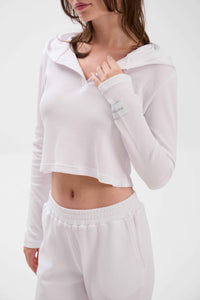 Woman wearing a white long-sleeve crop top and pants on a white background.