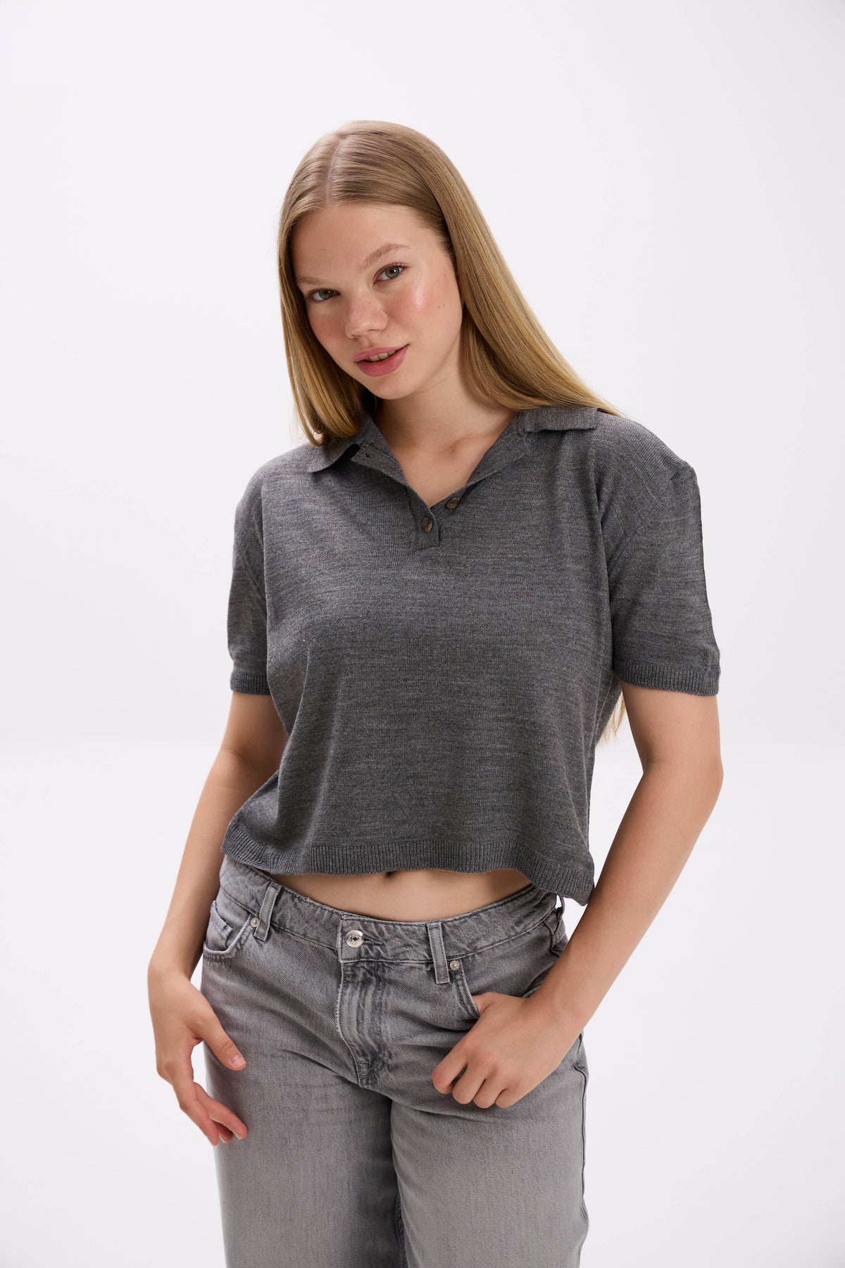 Woman wearing a gray polo shirt and jeans on a white background