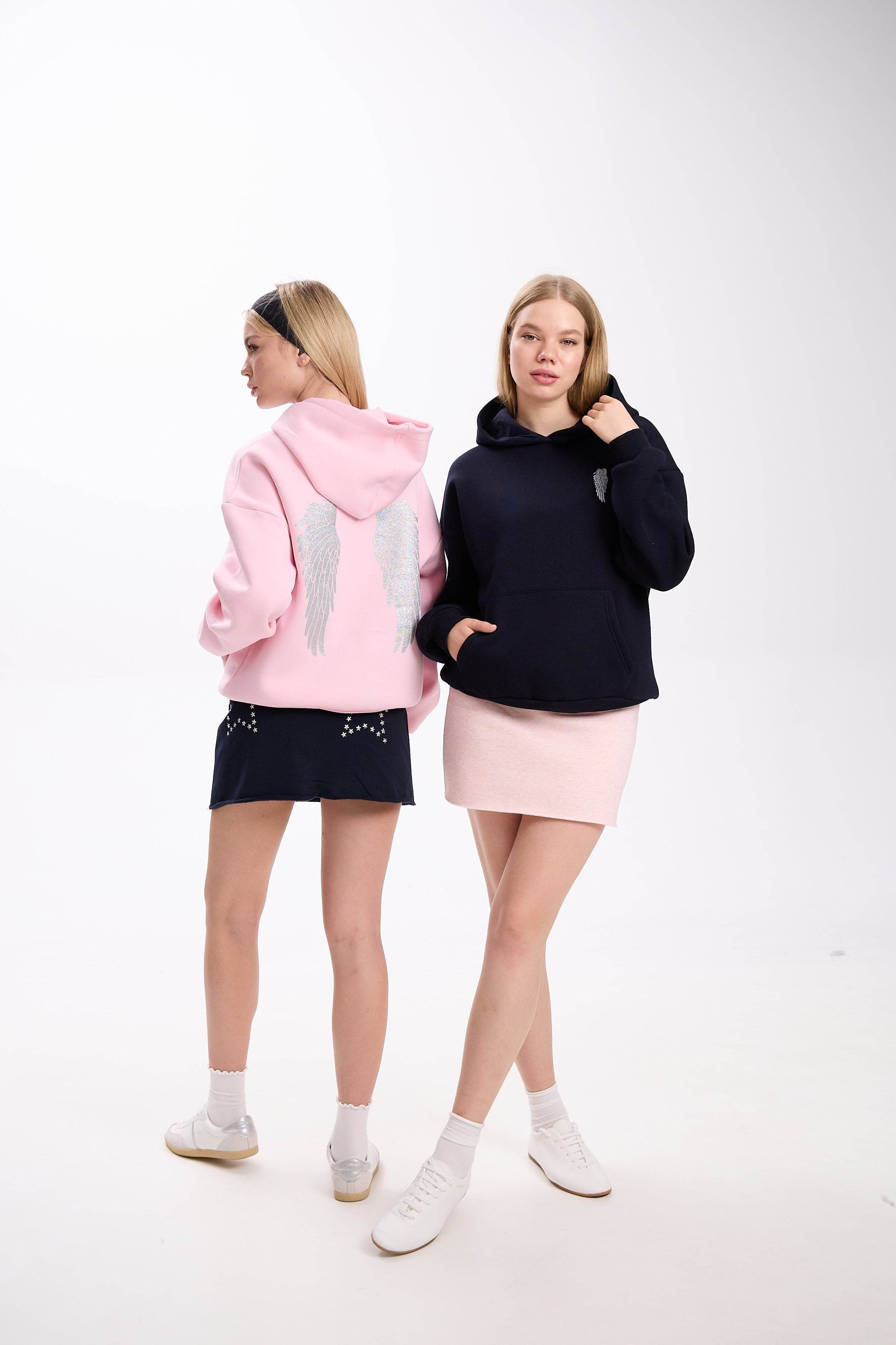 model dressed in a white hoodie featuring a star patch design, combined with a fitted white mini skirt and sneakers, showcasing a clean and minimal look on a white background.