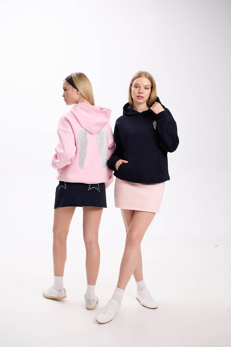 model dressed in a white hoodie featuring a star patch design, combined with a fitted white mini skirt and sneakers, showcasing a clean and minimal look on a white background.