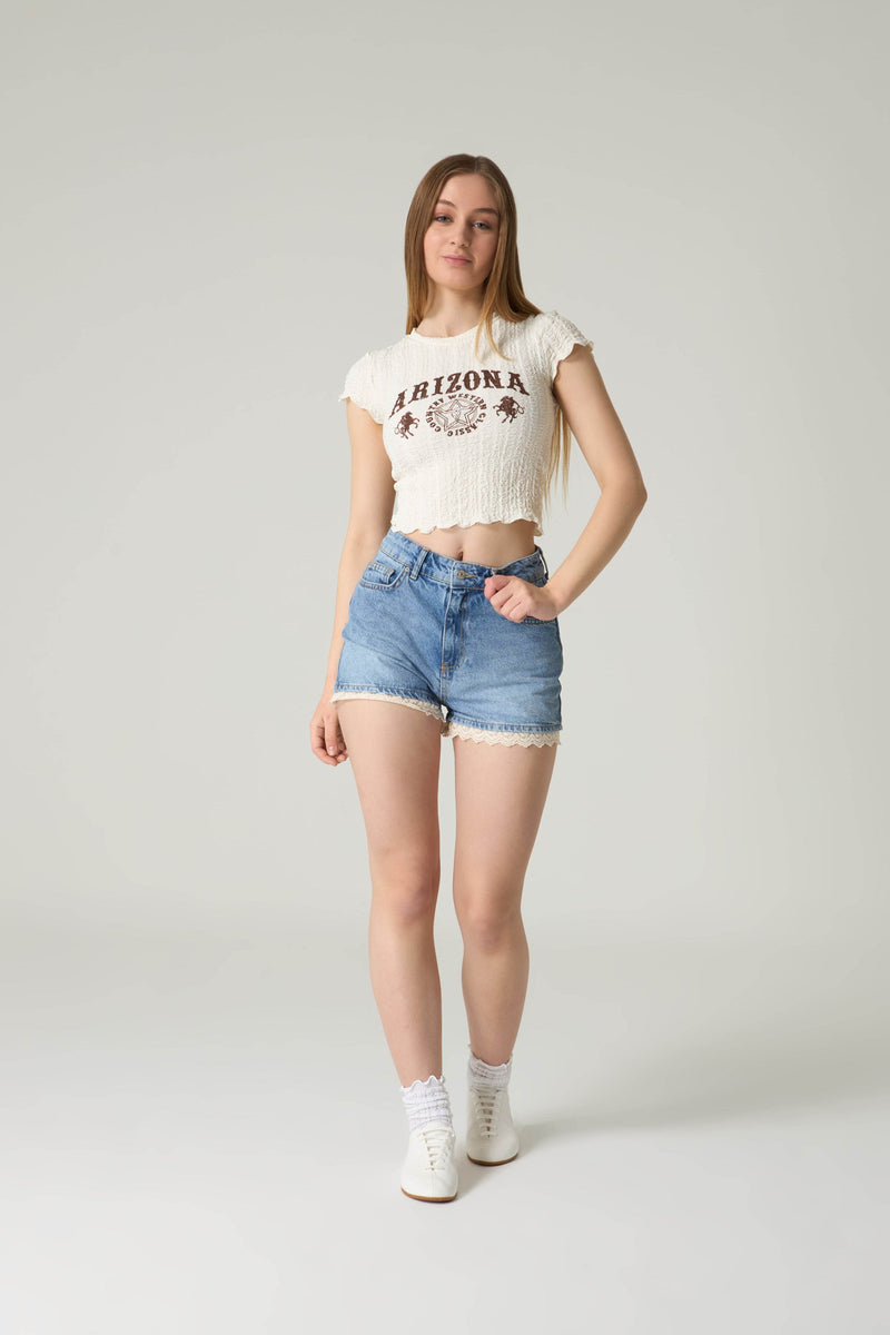 Person wearing a white t-shirt with 'Arizona' print and denim shorts on a plain background.