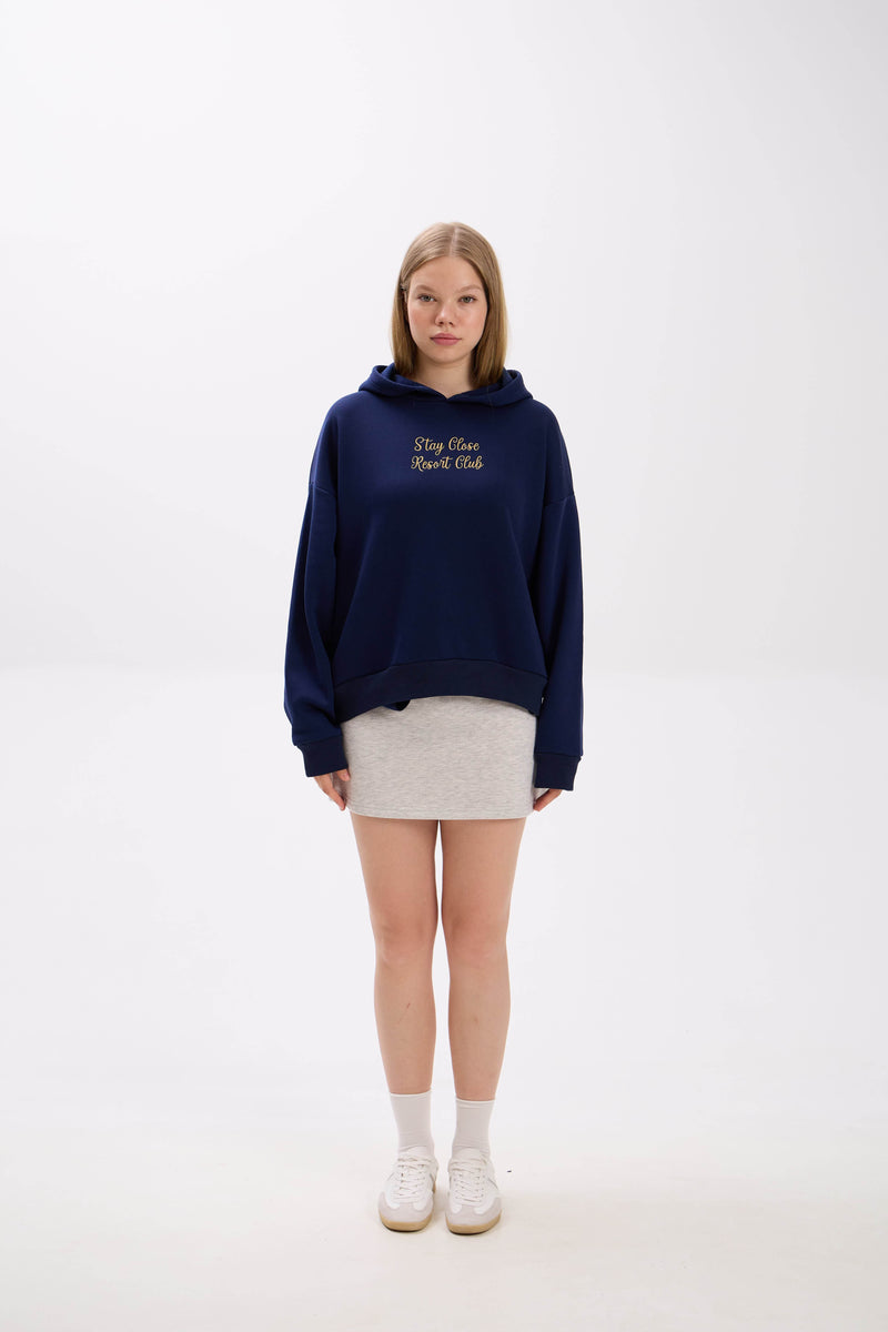 Person wearing a navy hoodie and grey melange skirt with text on a white background