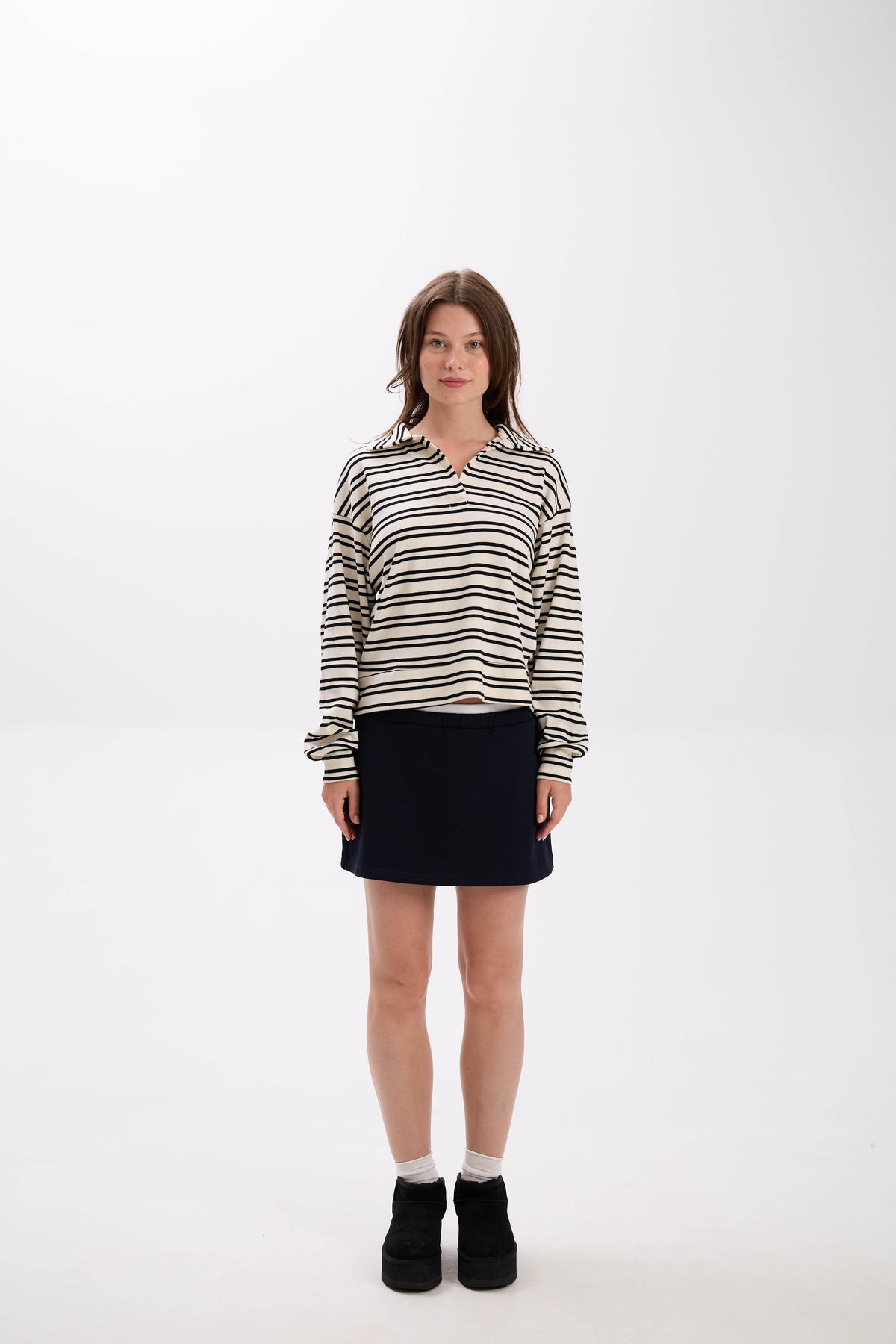 Woman wearing a striped shirt and black skirt on a white background