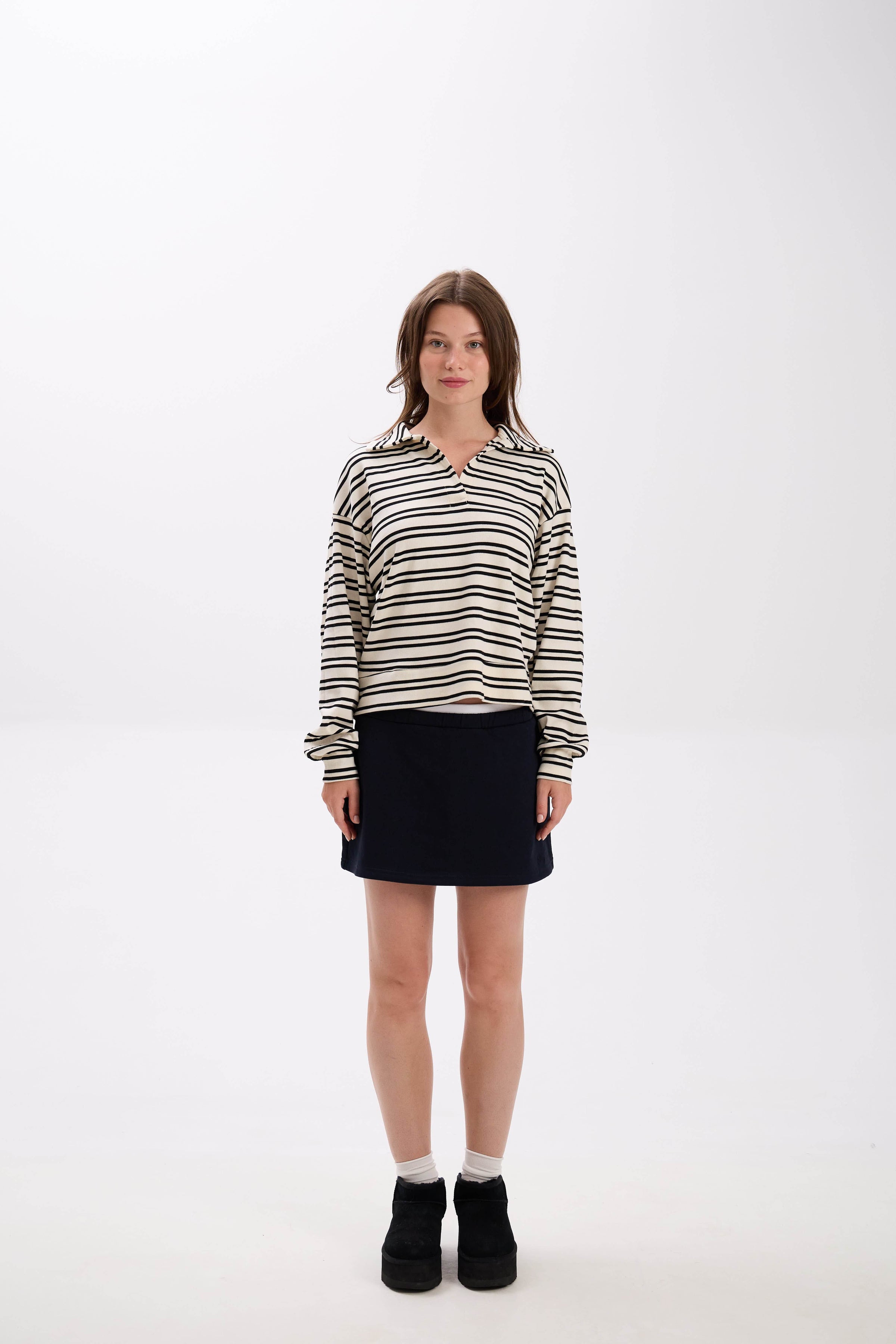 Woman wearing a striped shirt and black skirt on a white background