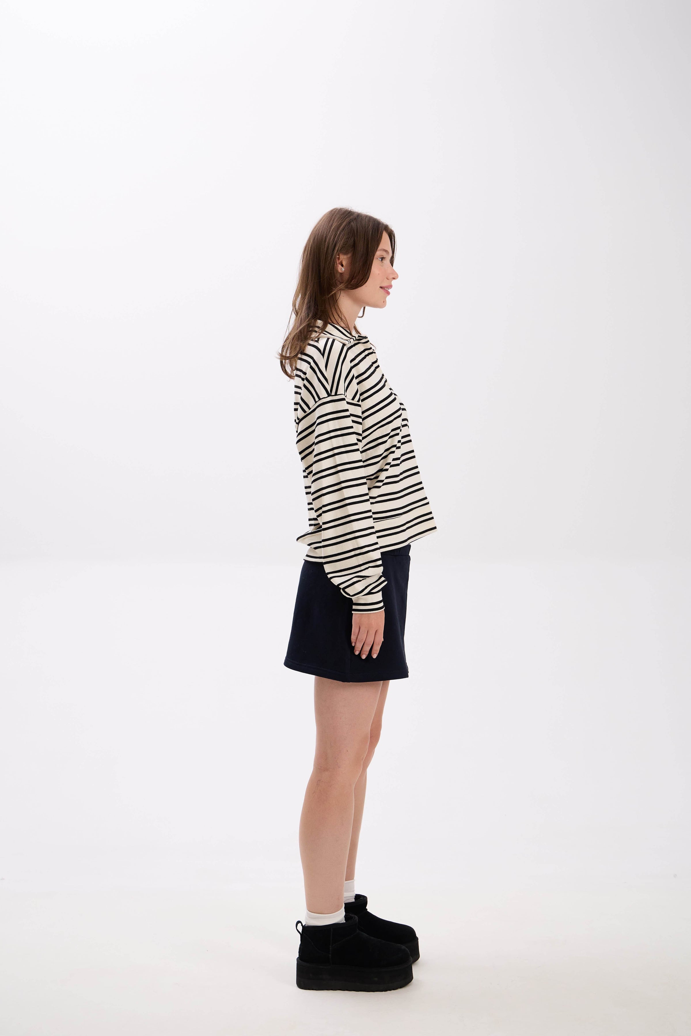 Person wearing a striped shirt and black skirt on a white background