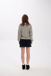 Person wearing a striped sweater and black skirt on a white background