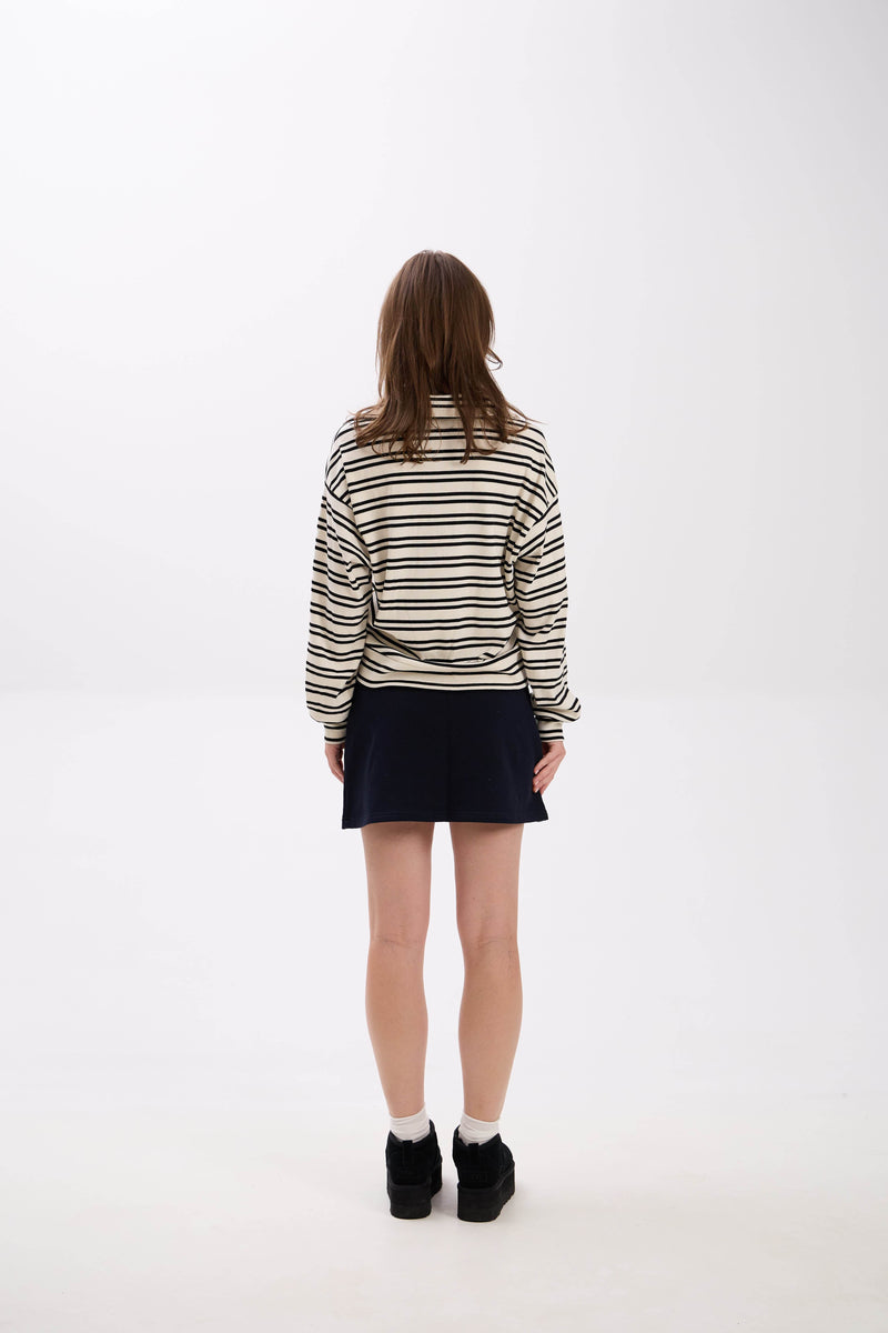 Person wearing a striped sweater and black skirt on a white background