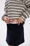 Person wearing a striped sweater and black skirt on a white background