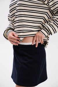 Person wearing a striped sweater and black skirt on a white background
