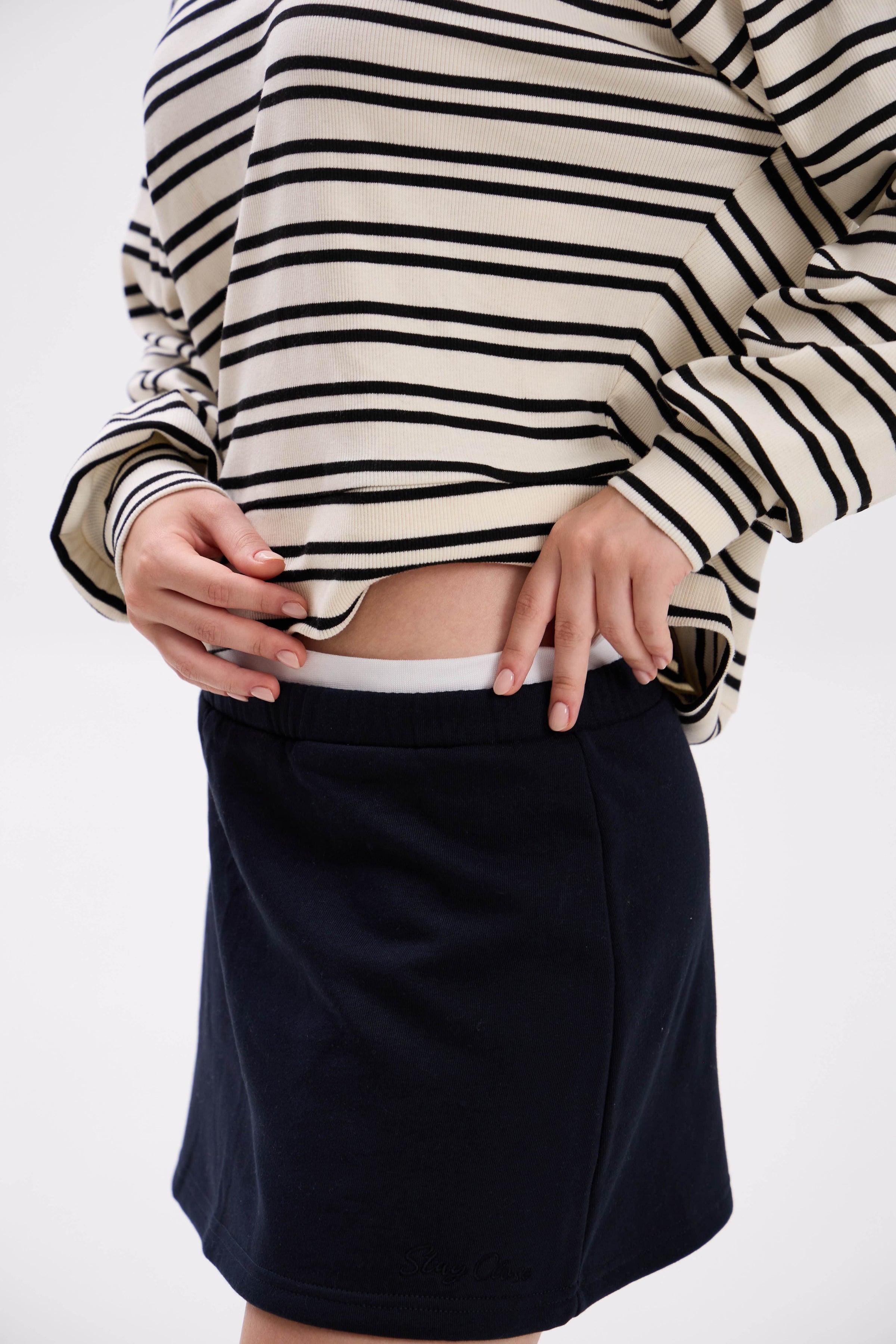 Person wearing a striped sweater and black skirt on a white background