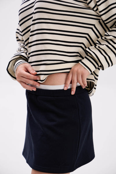 Person wearing a striped sweater and black skirt on a white background