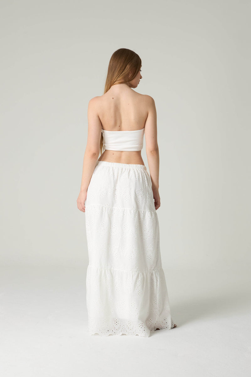 Woman wearing a white strapless top and skirt set on a plain background.