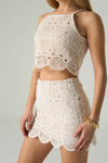 White crochet top and skirt set on a neutral background.