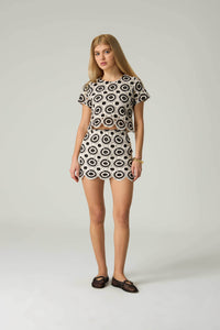 Woman wearing a patterned outfit on a plain background.