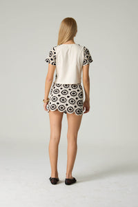 Woman wearing a patterned dress with a plain background.