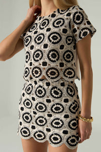 Woman wearing a black and white patterned dress on a plain background.