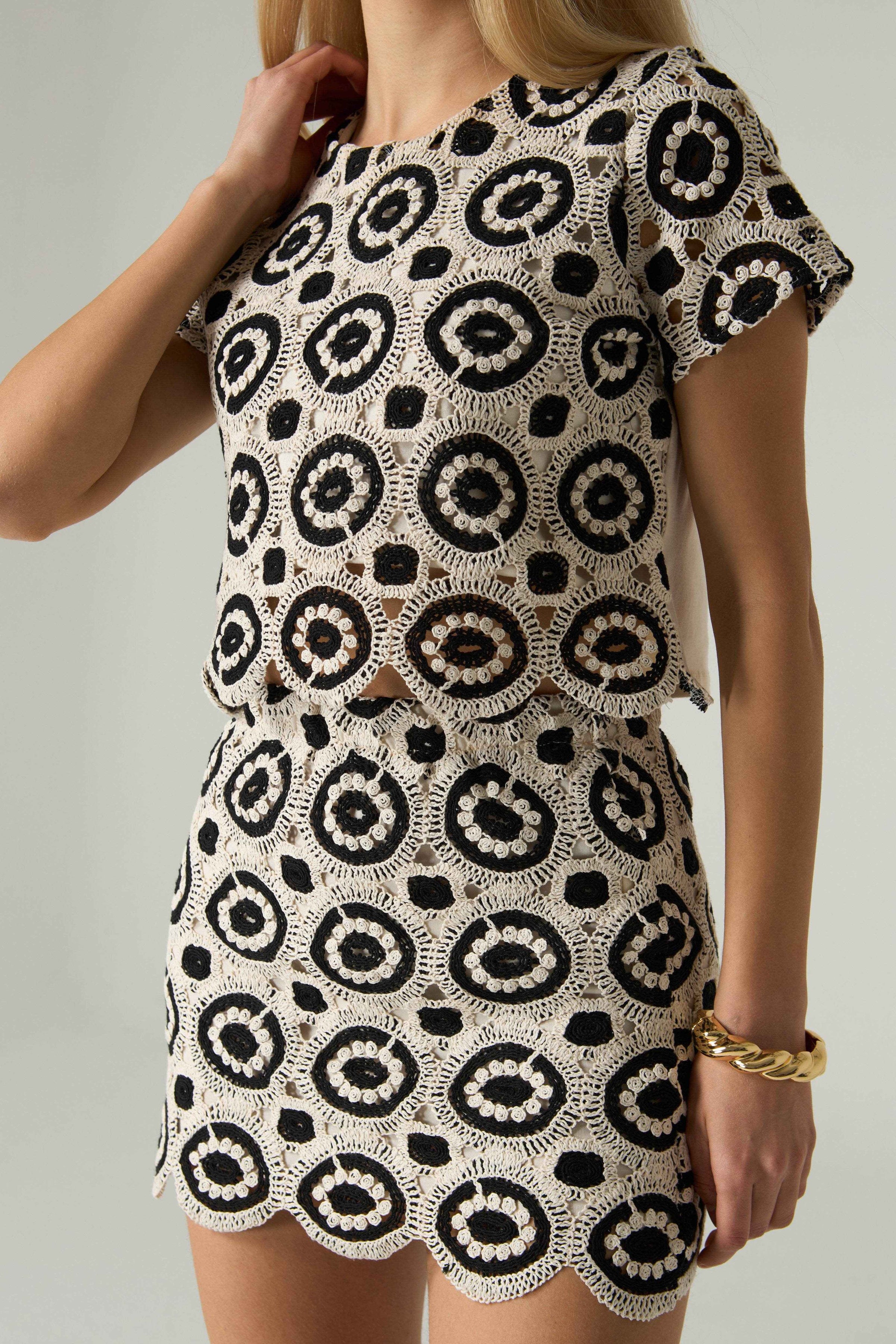 Woman wearing a black and white patterned dress on a plain background.