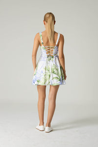 Woman wearing a floral dress with a white background.