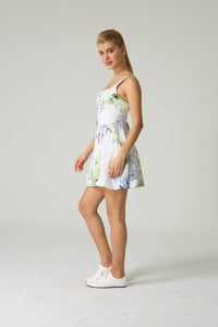 Woman wearing a floral dress on a plain background.