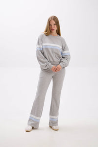 Woman wearing a gray lounge set with light blue stripes on a white background.