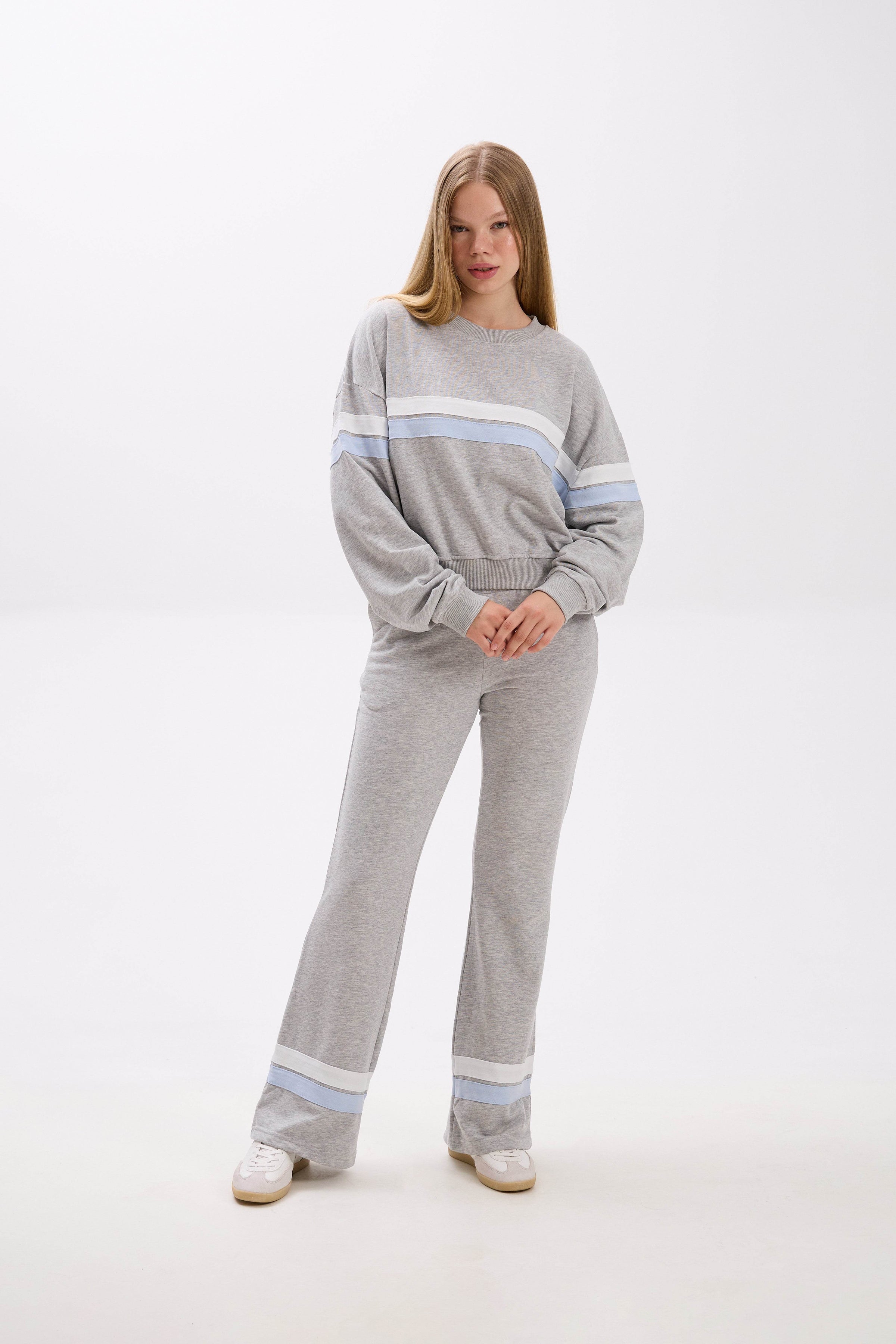 Woman wearing a gray lounge set with light blue stripes on a white background.
