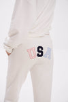 Light-colored sweatpants with colorful 'USA' design on a white background.
