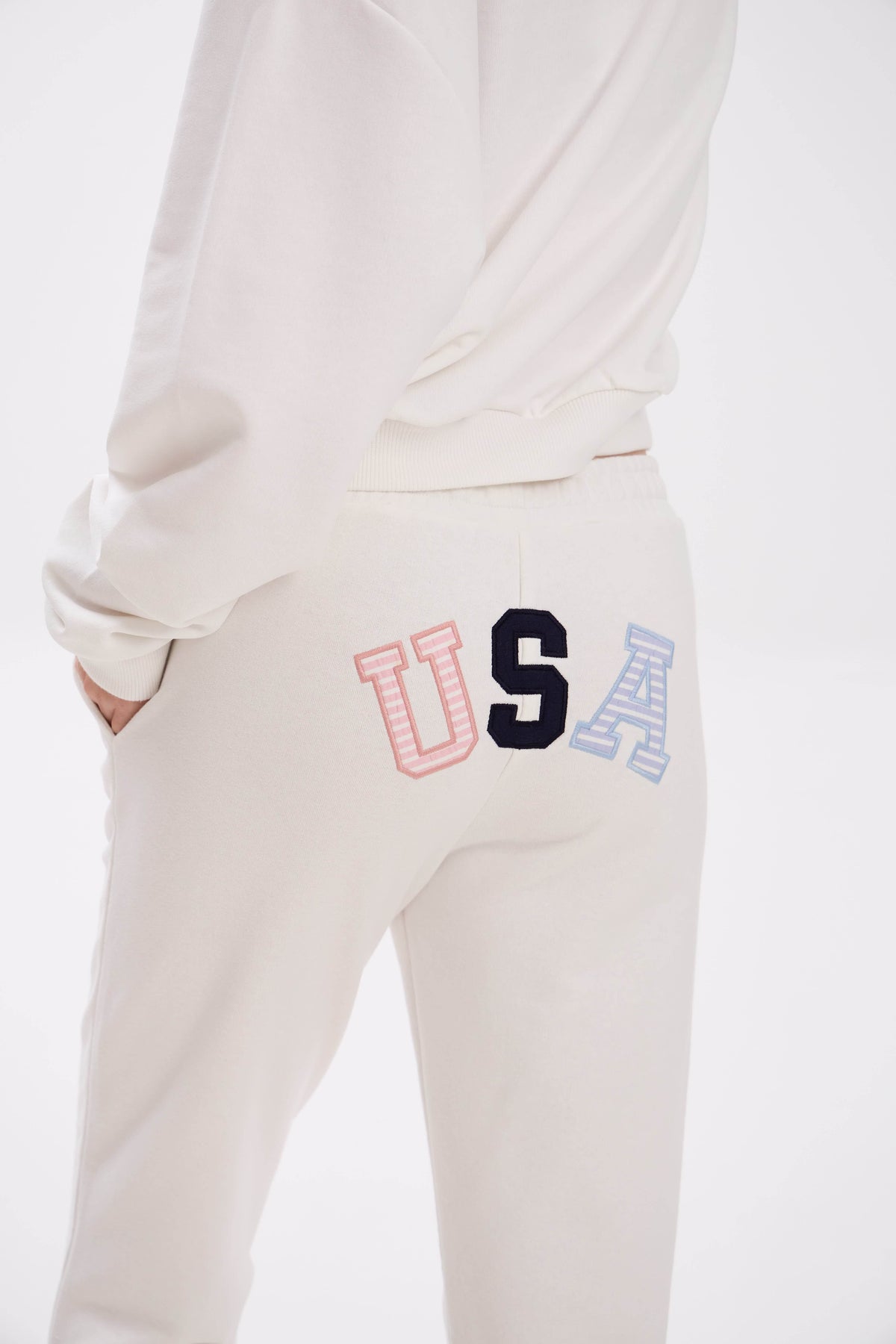 Light-colored sweatpants with colorful 'USA' design on a white background.
