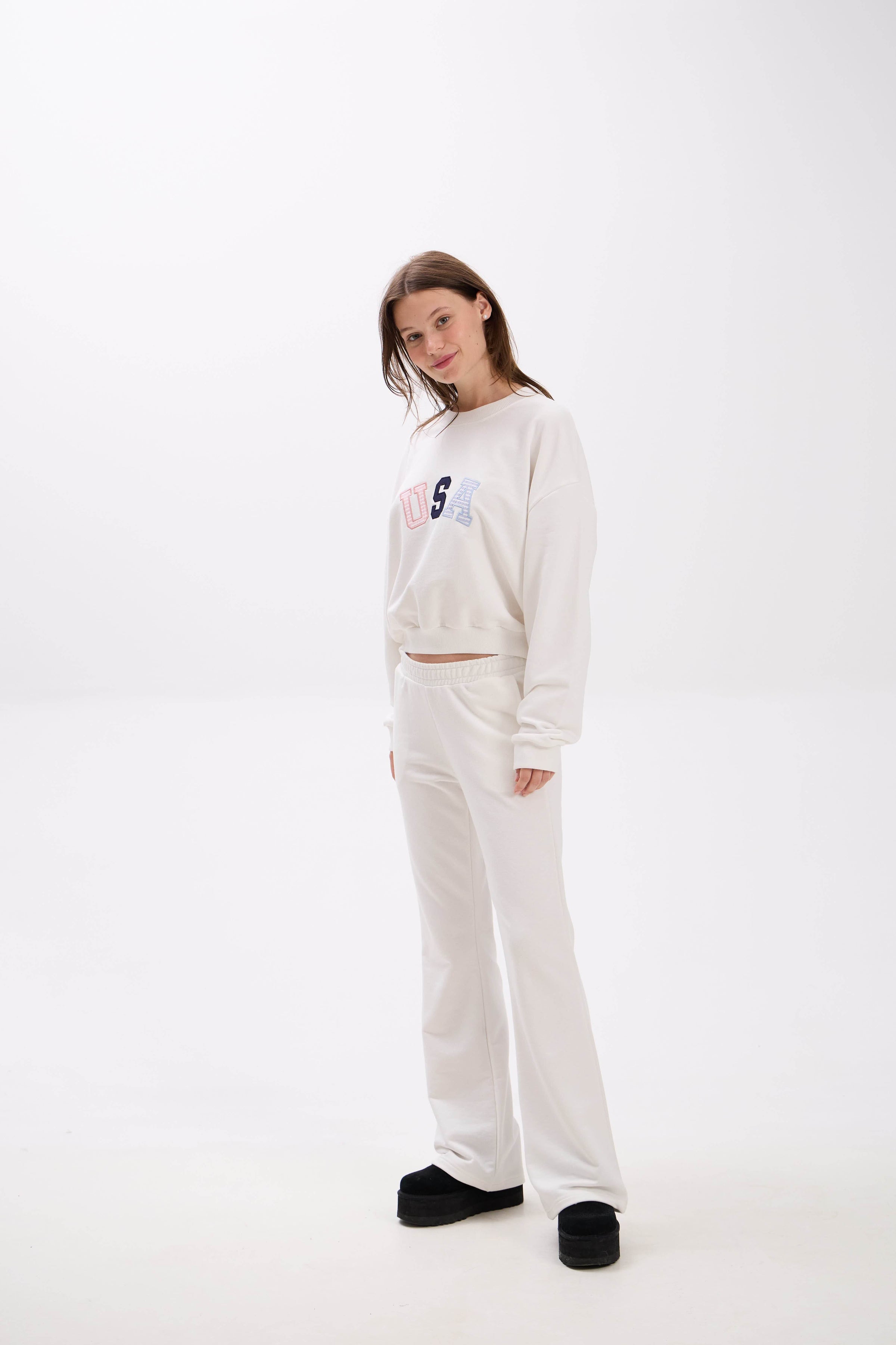 Person wearing a white sweatshirt and pants set on a white background.