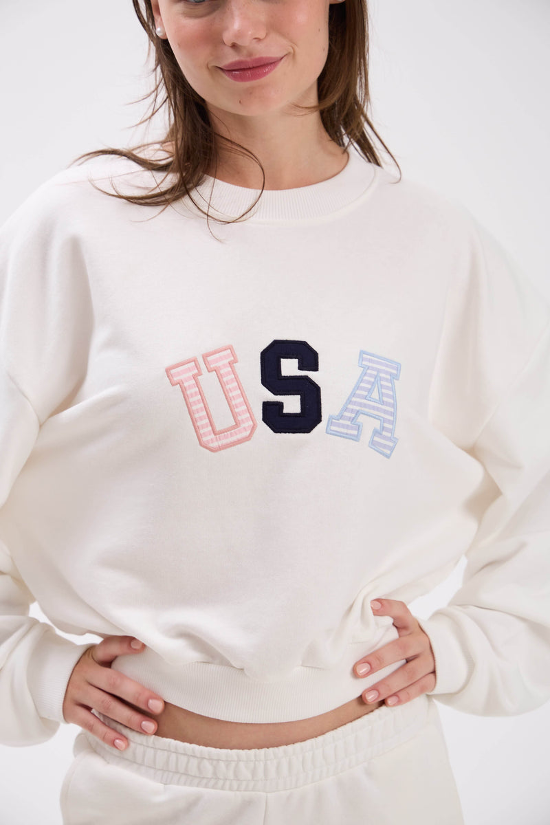 Person wearing a white sweatshirt with 'USA' in colorful letters.