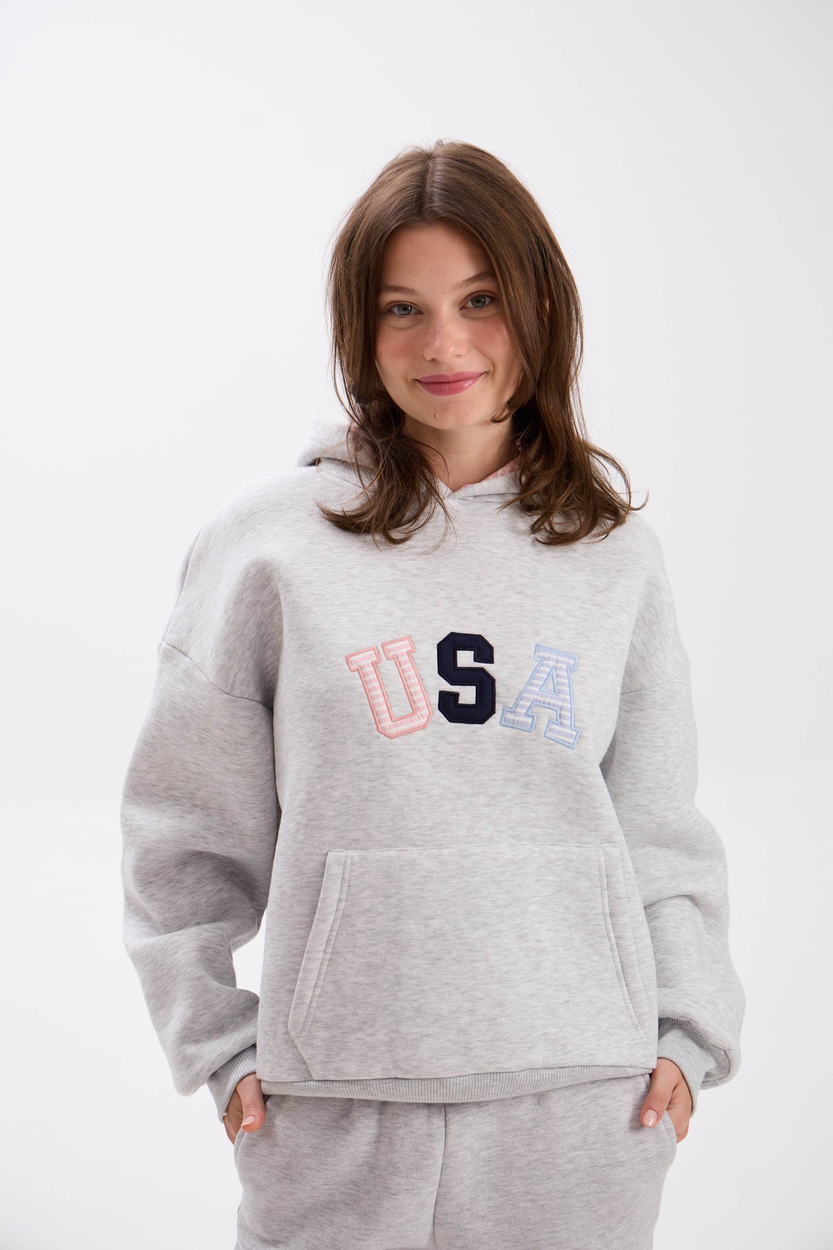 Person wearing a gray hoodie with multicolored 'USA' text on a white background.