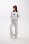 Woman wearing a gray hoodie and pants with colorful text on a white background.