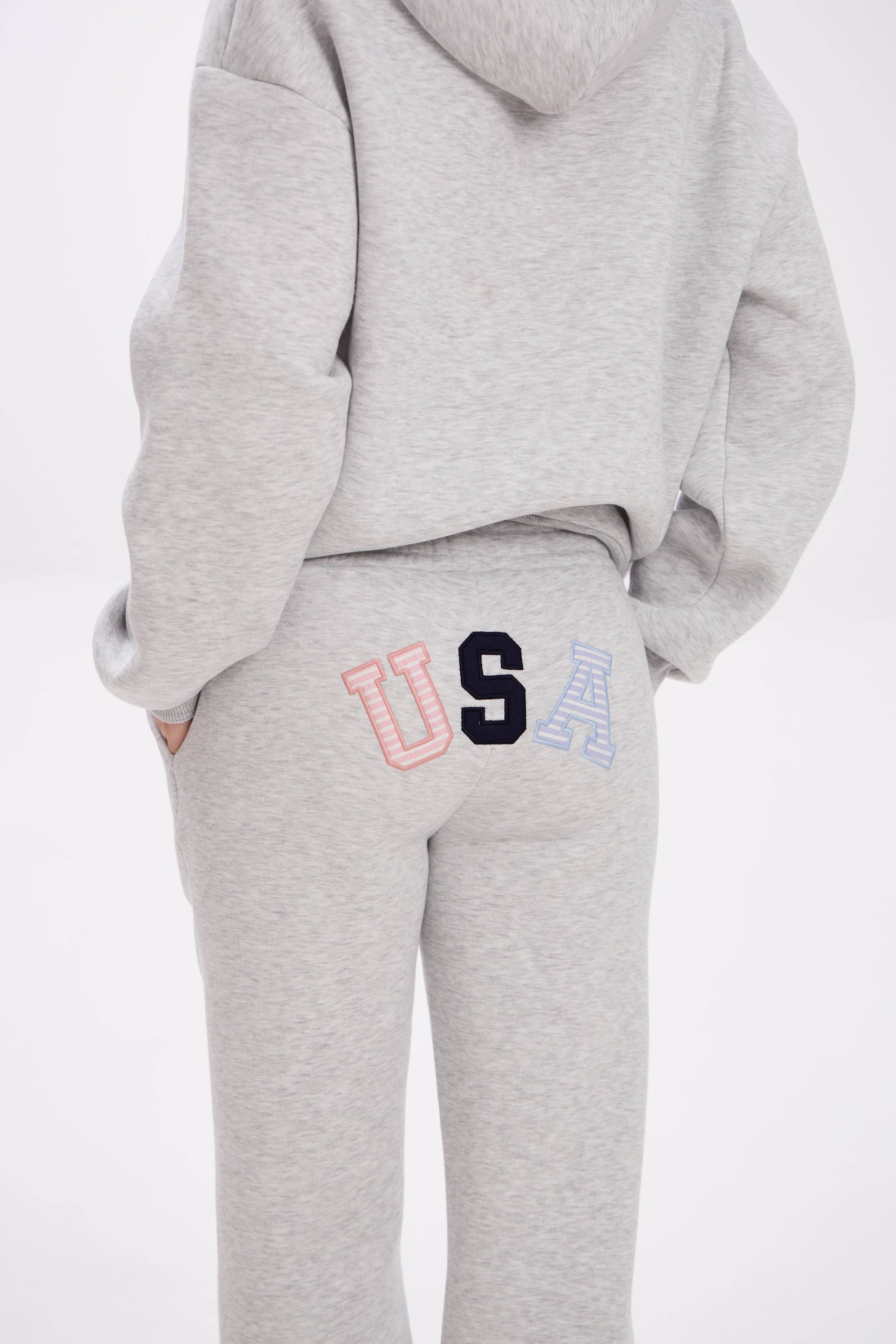 Grey hoodie and sweatpants with elastic waistband, side pockets, and multicolor USA lettering on the back.