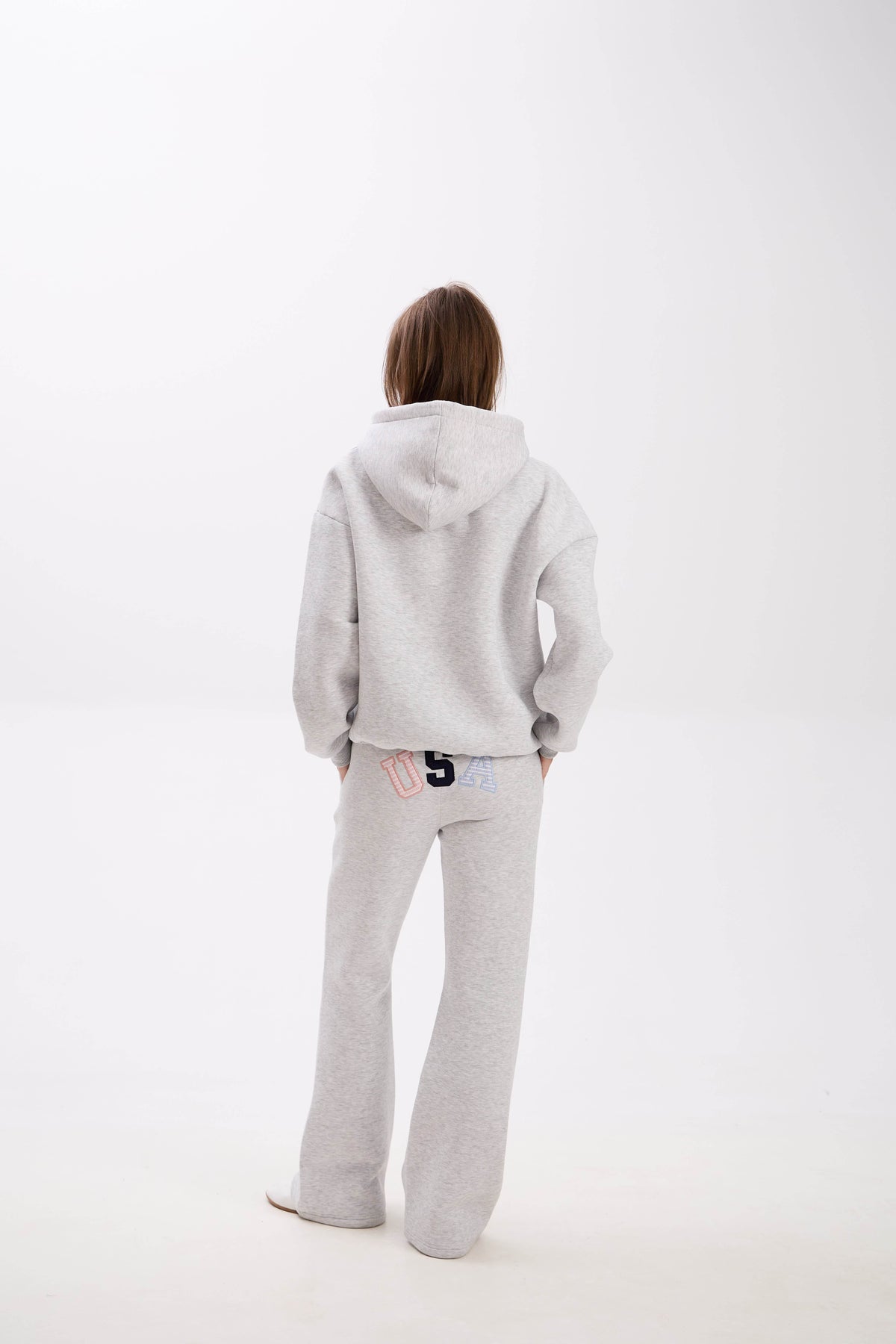 Grey hoodie and sweatpants with elastic waistband, side pockets, and multicolor USA lettering on the back.
