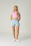 Woman wearing a pink crop top and light blue denim shorts on a white background.