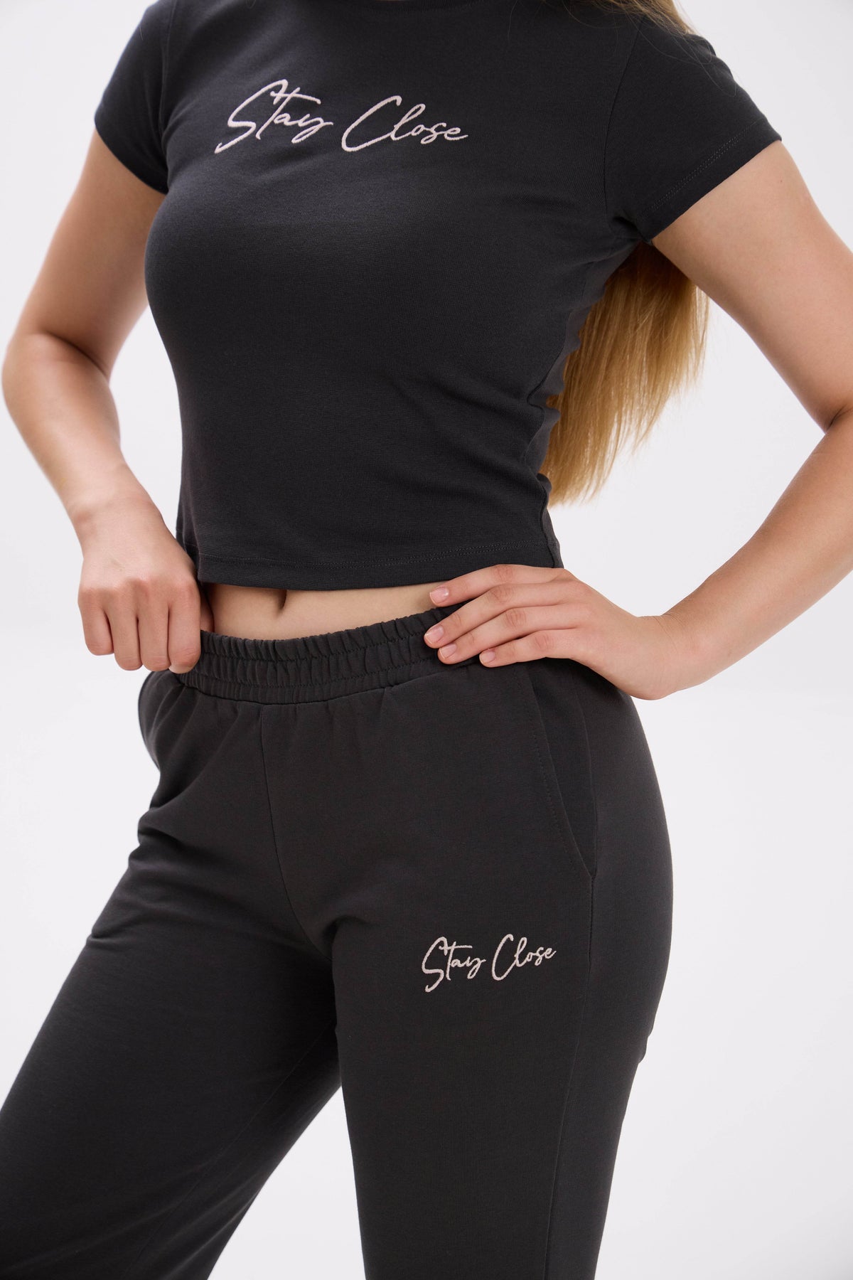 Person wearing black 'Stay Close' t-shirt and pants on a white background.