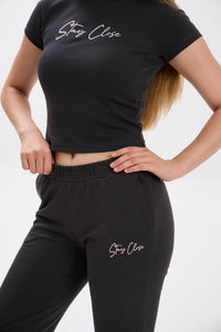 Person wearing black 'Stay Close' t-shirt and pants on a white background.