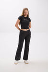 Woman wearing a black crop top and pants with a "Stay Close" embroidery on a white background.