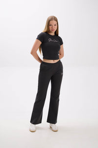Woman wearing a black crop top and pants with a "Stay Close" embroidery on a white background.
