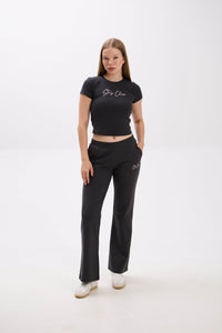 Woman wearing a black crop top and pants with "Stay Close" embroidery on a white background.