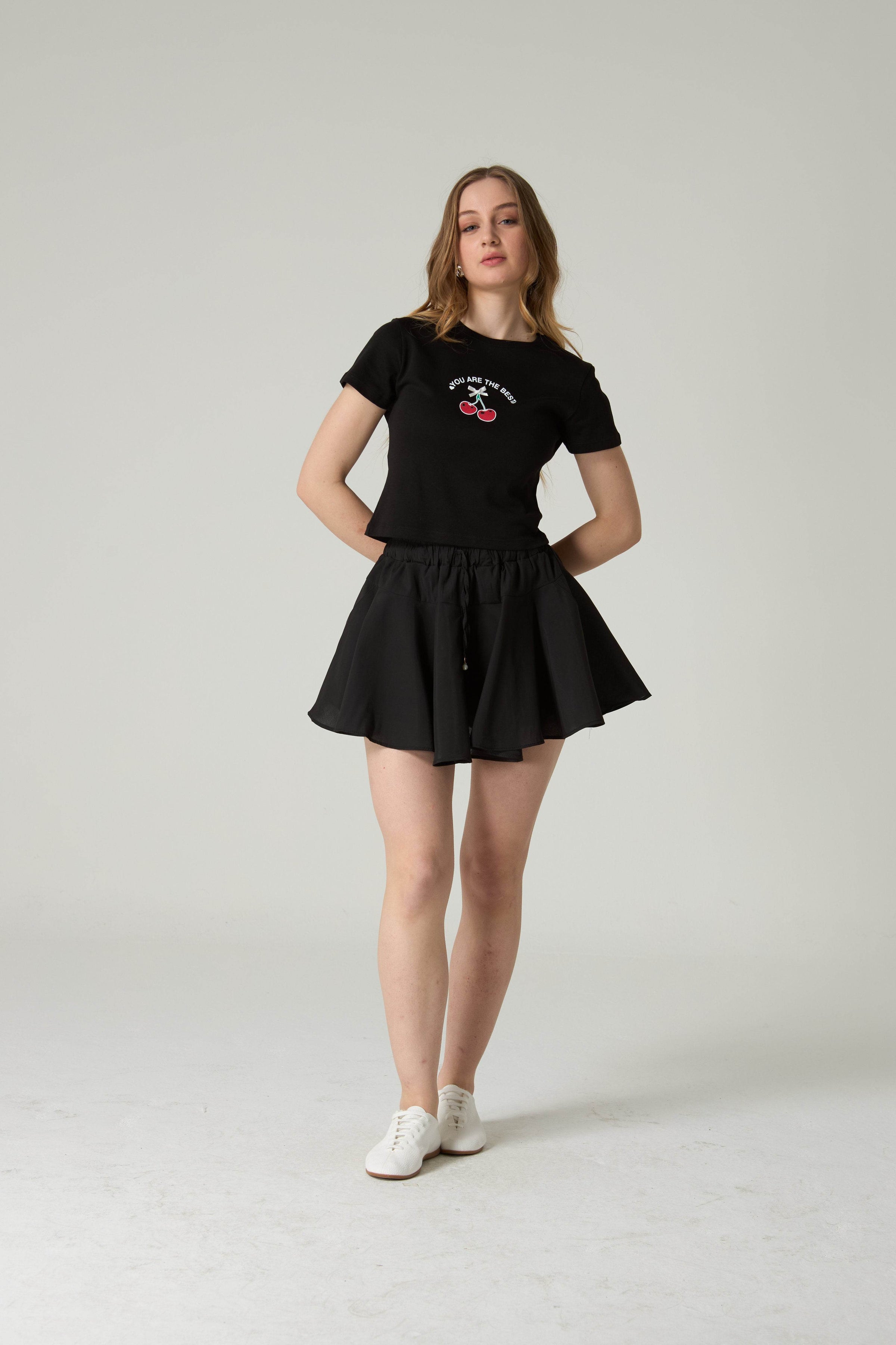 Woman wearing a black t-shirt and skirt set on a plain background.