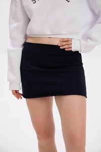Person wearing a black mini skirt and white sweatshirt on a plain background