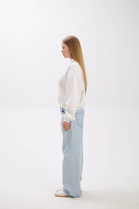 Woman wearing a white blouse and light blue pants on a white background