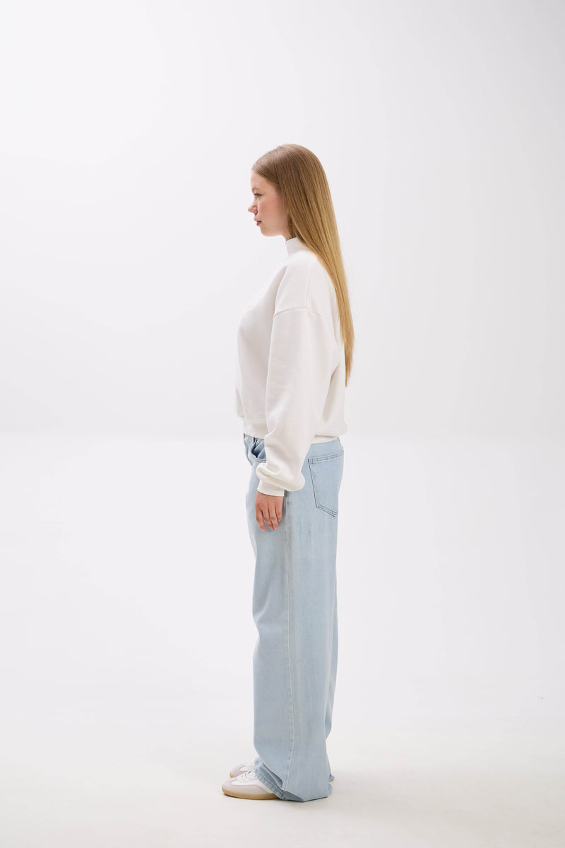 Woman wearing a white blouse and light blue pants on a white background