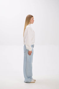 Woman wearing a white blouse and light blue pants on a white background