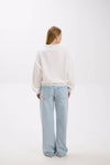 Person wearing a white sweater and light blue jeans on a white background