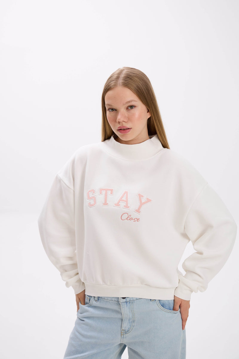 Person wearing a white sweatshirt with 'STAY Close' text on a white background