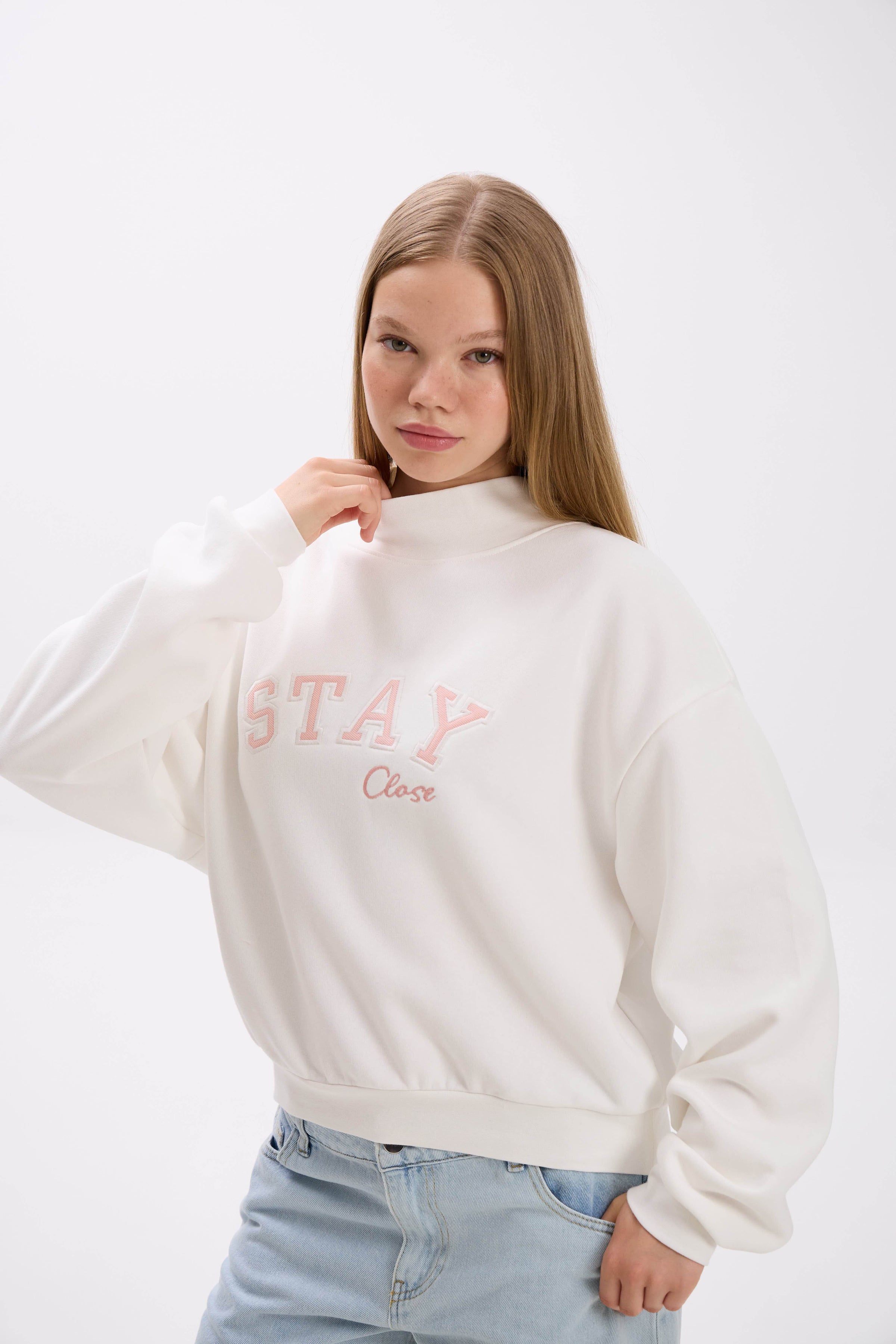 Person wearing a white sweatshirt with pink text on a white background